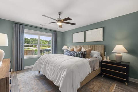 A bedroom with a large bed and a ceiling fan.