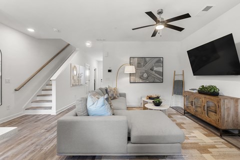 A living room with a grey couch and a ceiling fan.
