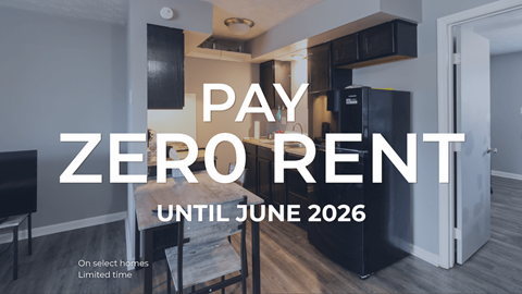A sign that says "PAY ZERO RENT UNTIL JUNE 2026" is displayed in a room with a kitchen area.