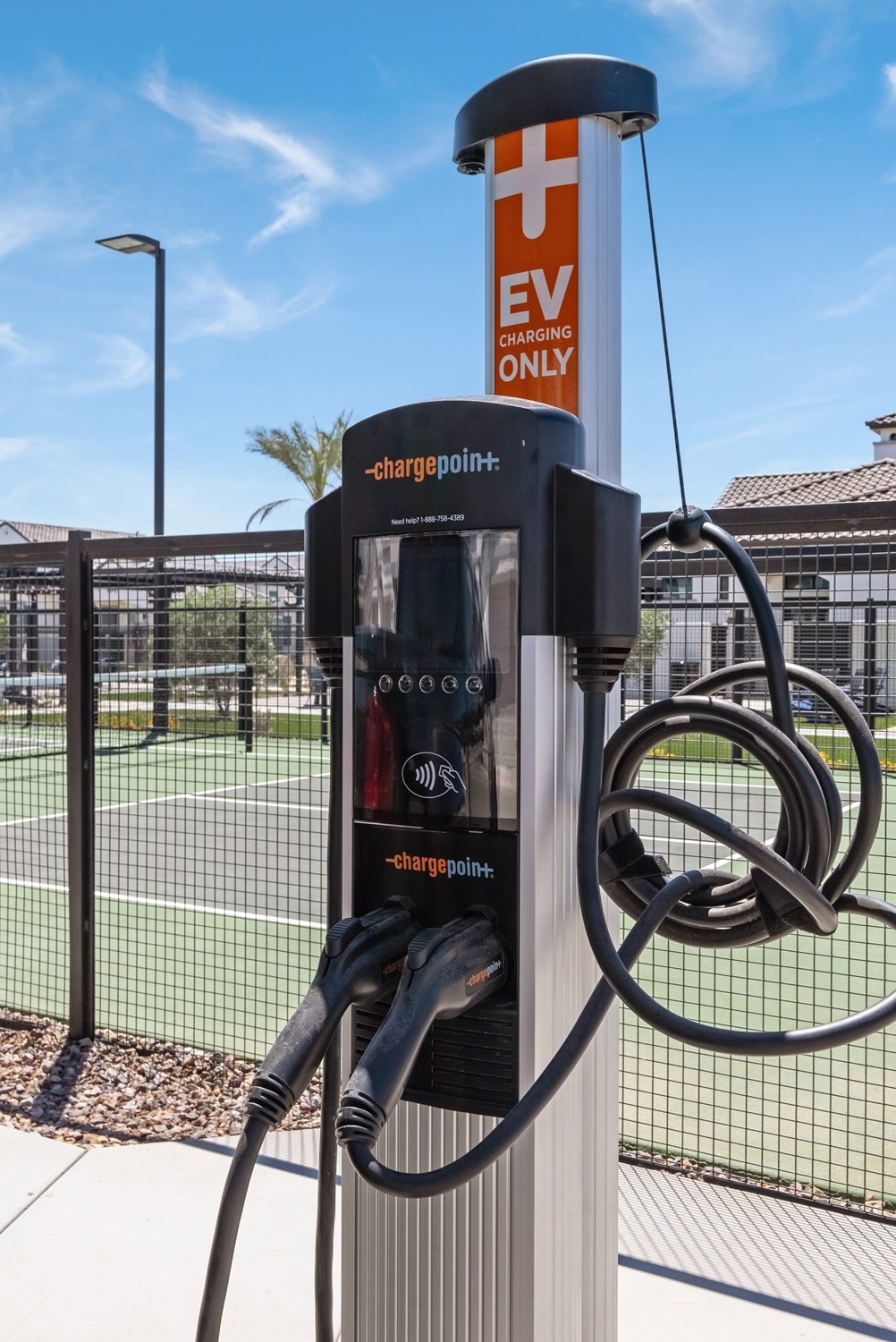 A ChargePoint EV charging station is located next to a tennis court.