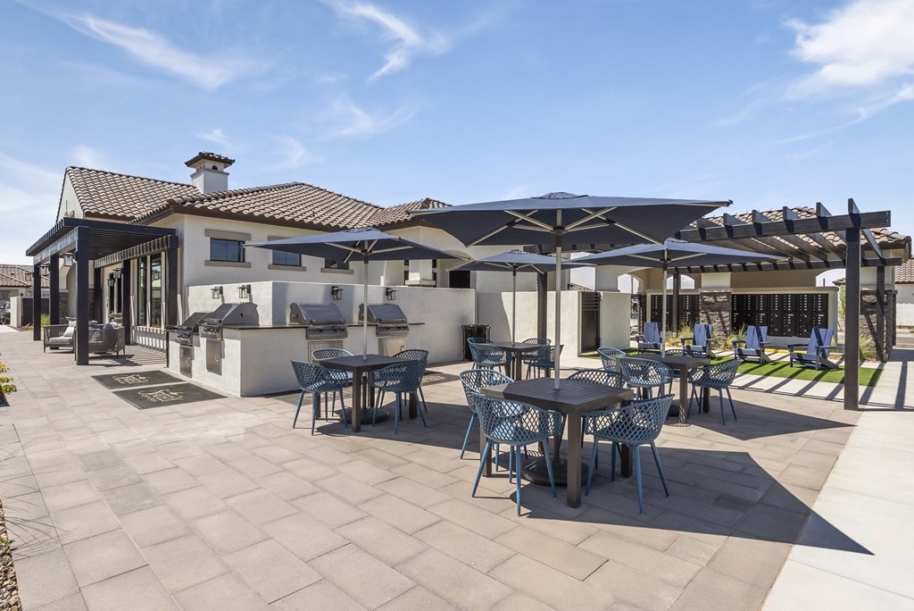 A patio with tables and chairs is shaded by umbrellas.