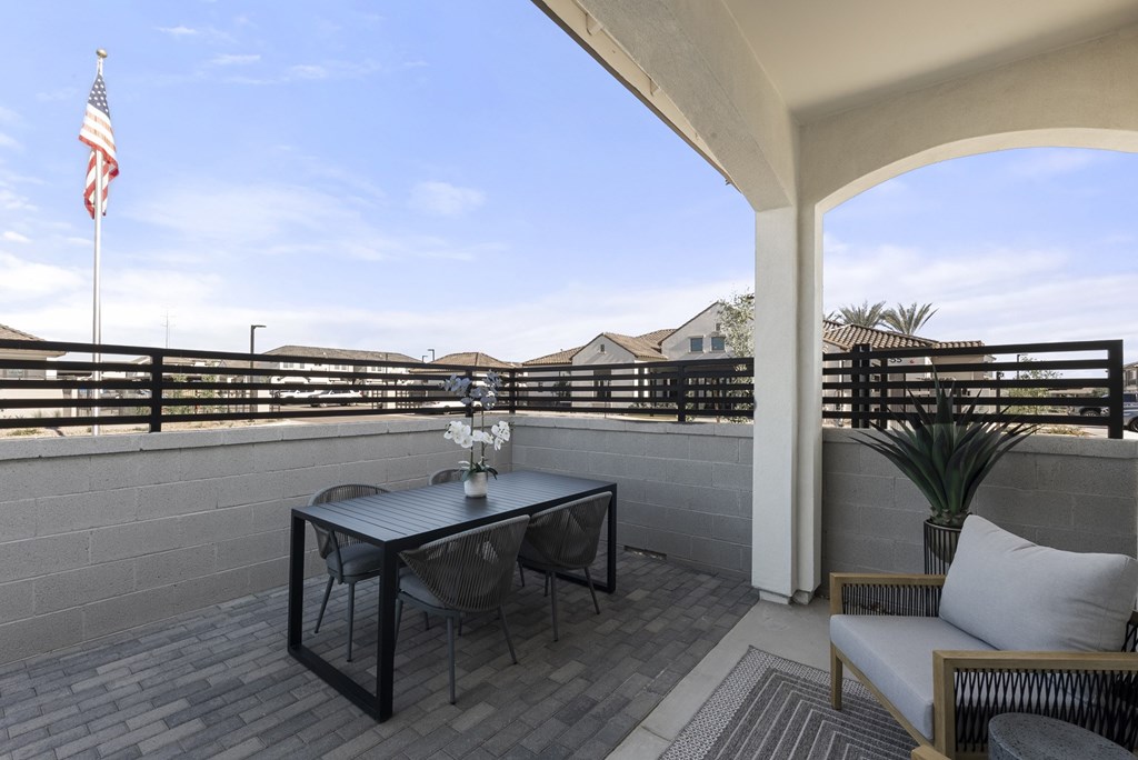 A balcony with a table, chairs, and an American flag.