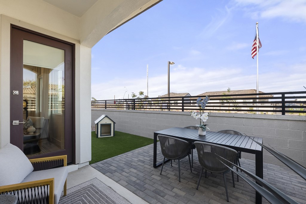 A patio with a table and chairs overlooking a balcony.