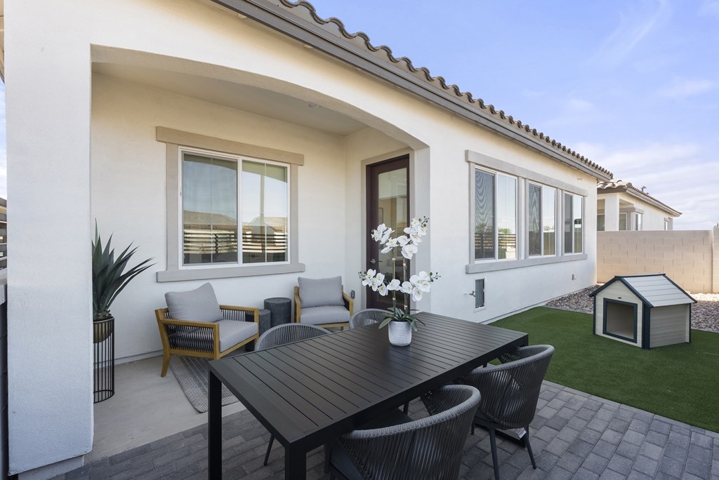 A patio with a table and chairs is set up outside a house.
