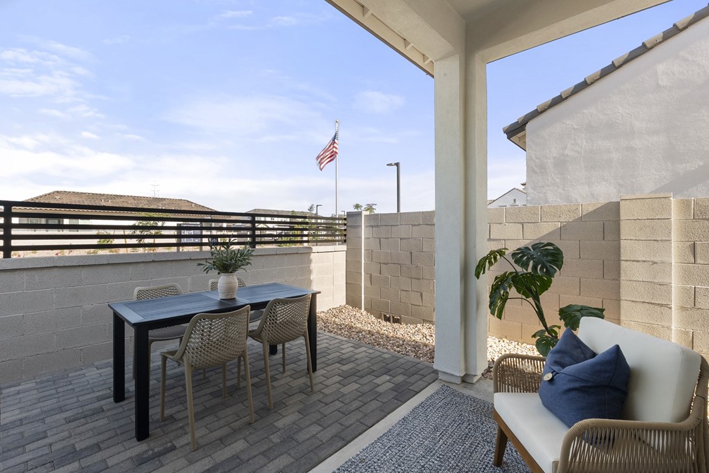 A patio with a table, chairs, and a couch with a pillow on it.