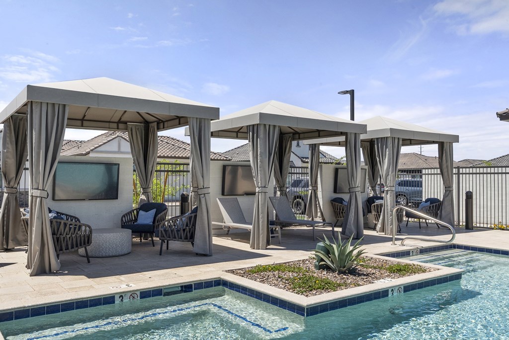 A pool area with a white canopy and a small pond.