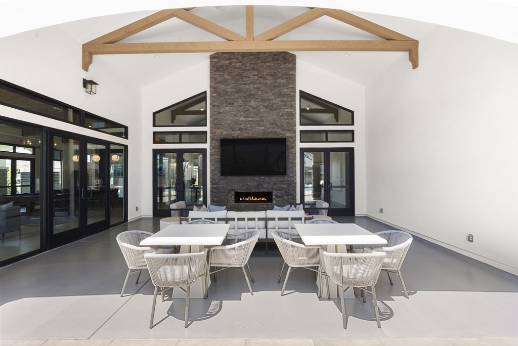 A modern dining room with a stone fireplace and white furniture.