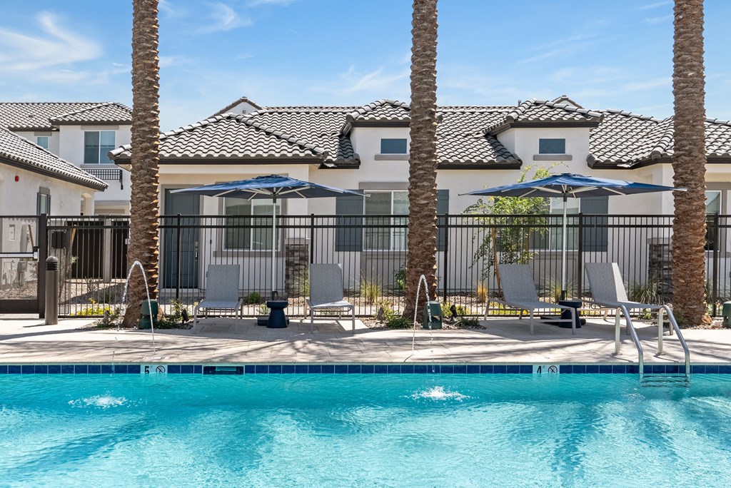 A pool surrounded by palm trees and lounge chairs.