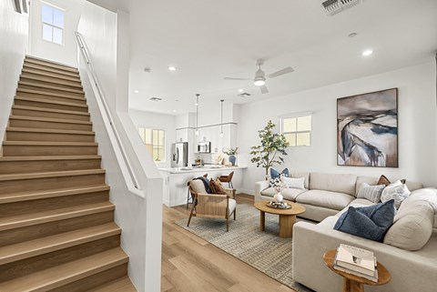A living room with a staircase and a painting on the wall.