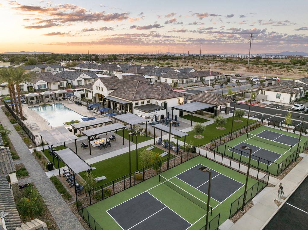 A tennis court surrounded by a fence and a pool in the background.