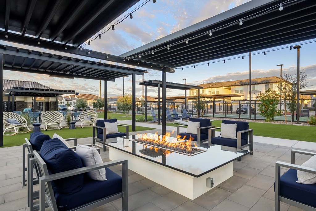 A patio with a fire pit and chairs.