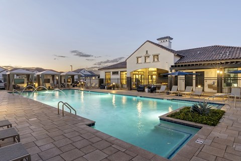 A large swimming pool surrounded by lounge chairs and umbrellas.