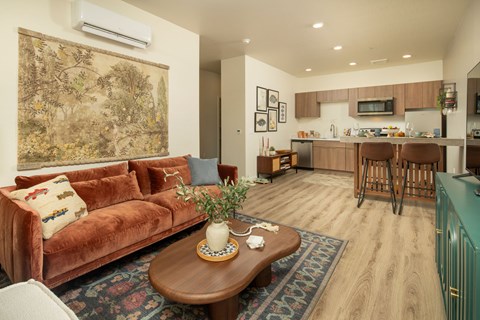 A living room with a brown couch and a coffee table with a vase on it.