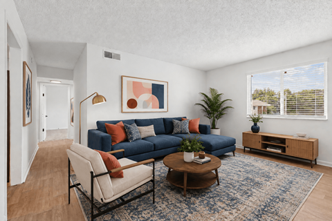 A living room with a blue couch and a painting on the wall.