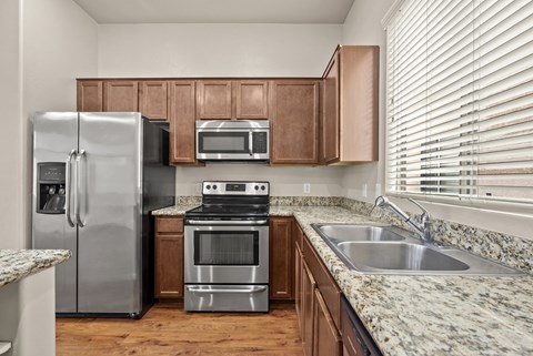 A kitchen with a stainless steel refrigerator, microwave, oven, and sink.