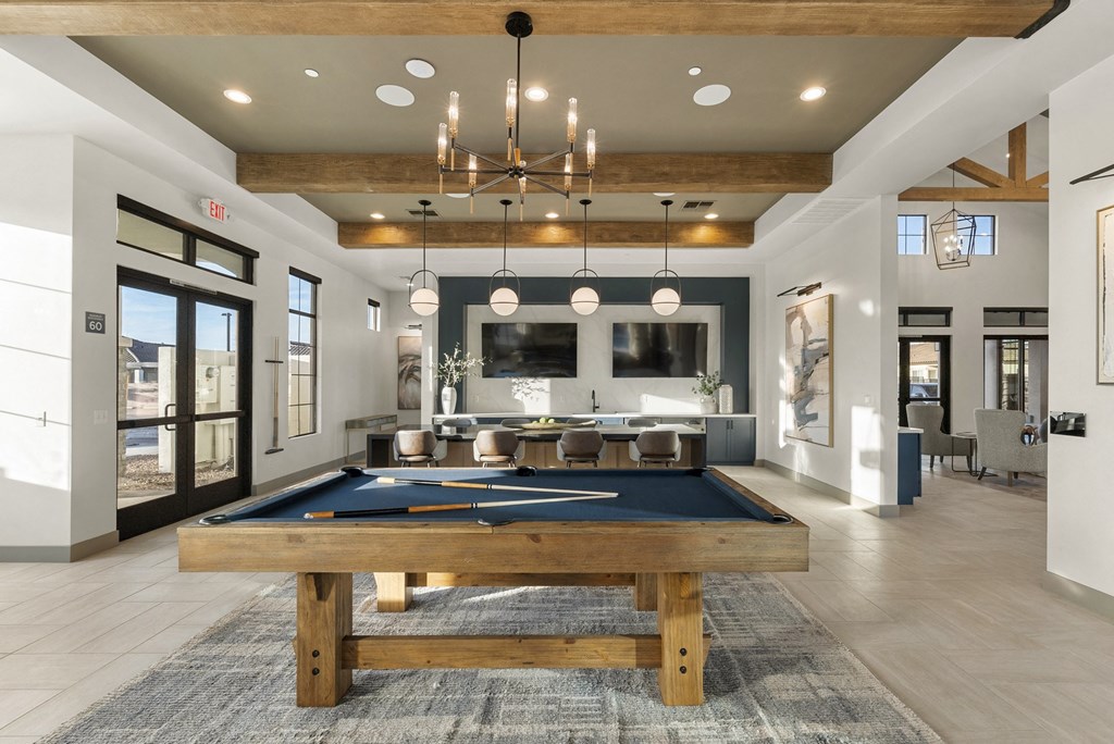 A pool table is in the middle of a room with a bar and a dining table.