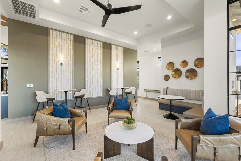 A living room with a fan, chairs, and a table.