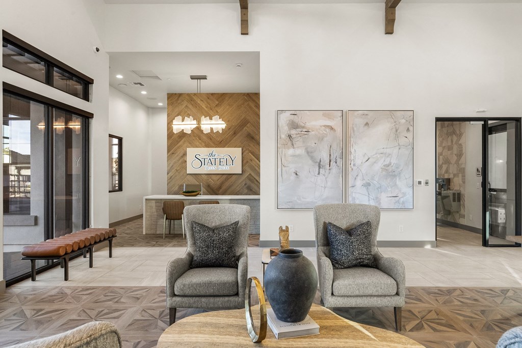Two grey chairs with pillows sit in front of a wooden sign that says "STATELY".