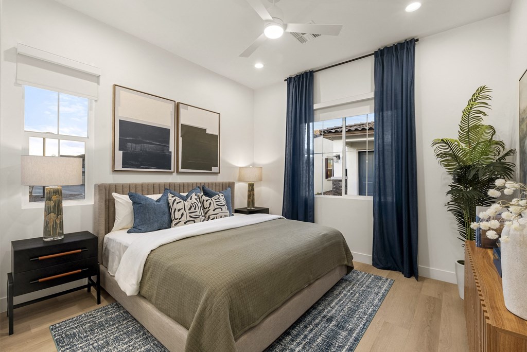 A bedroom with a large bed and a window with blue curtains.