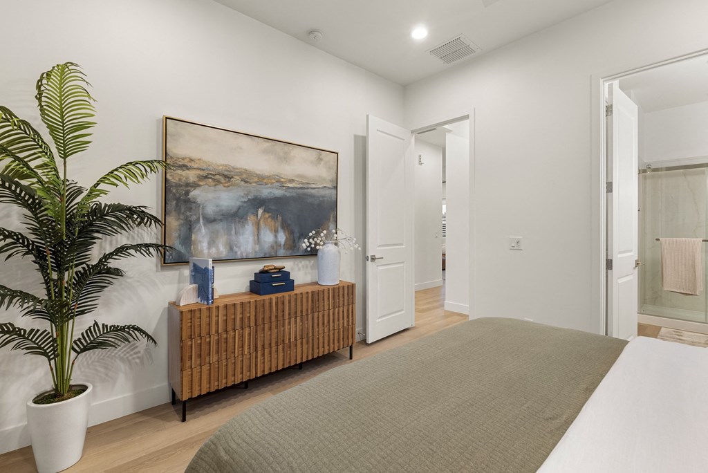 A room with a large painting on the wall and a bench with a potted plant on it.