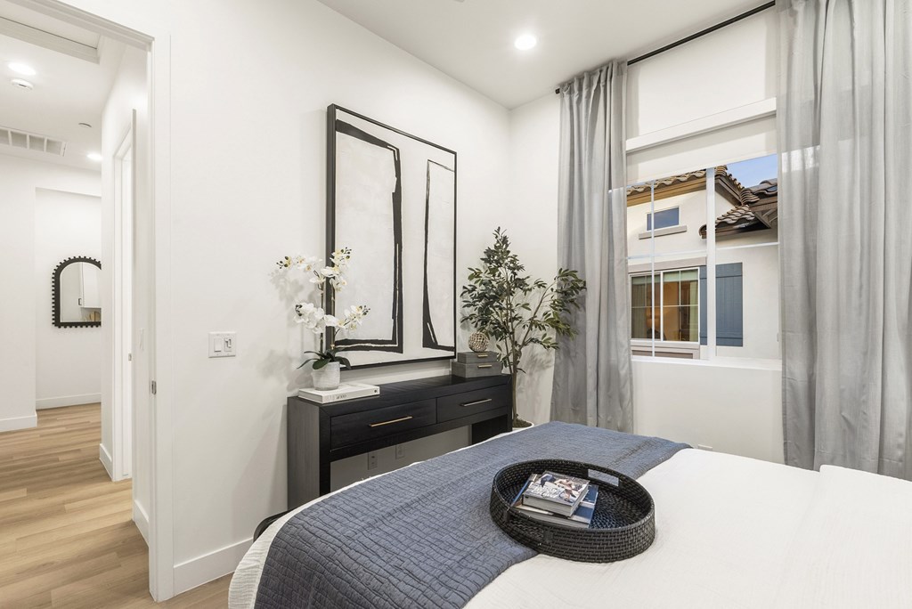 A bedroom with a bed, nightstand, and a window with curtains.