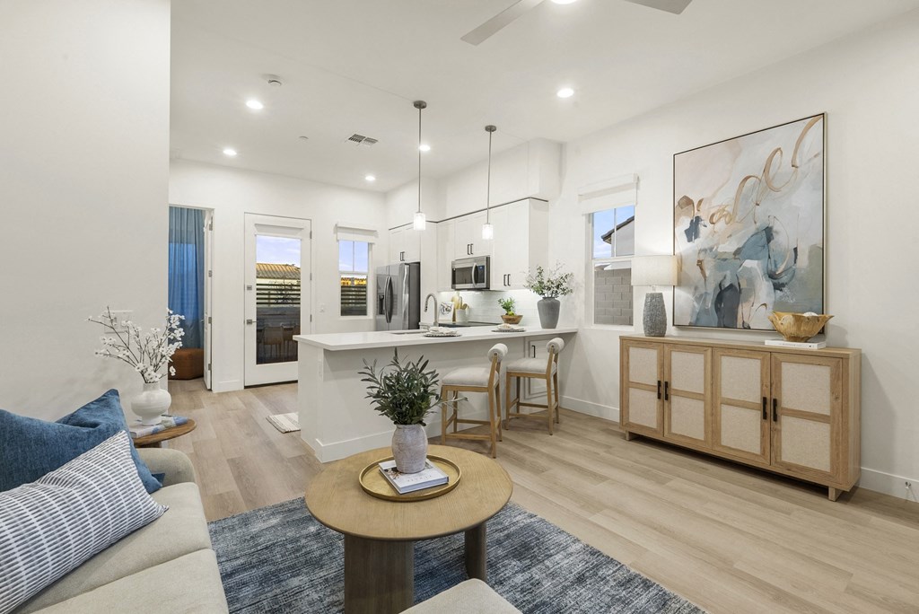 A living room with a white sofa, a wooden coffee table, and a painting on the wall.