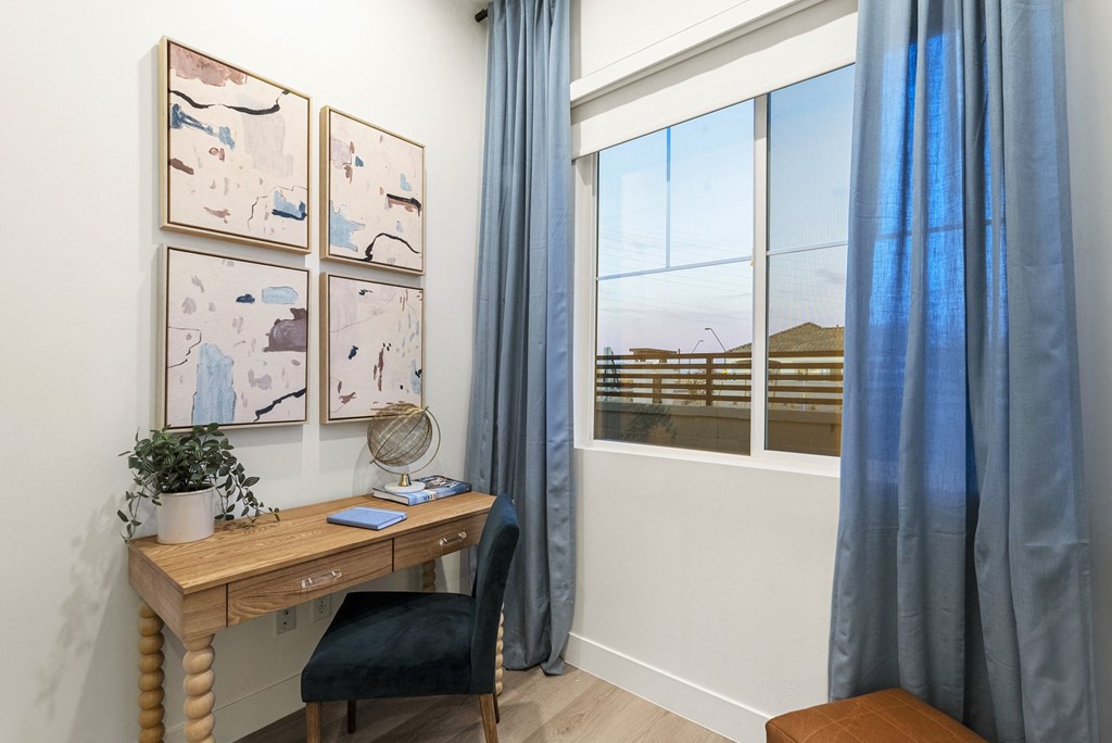 A room with a desk, chair, and pictures on the wall.