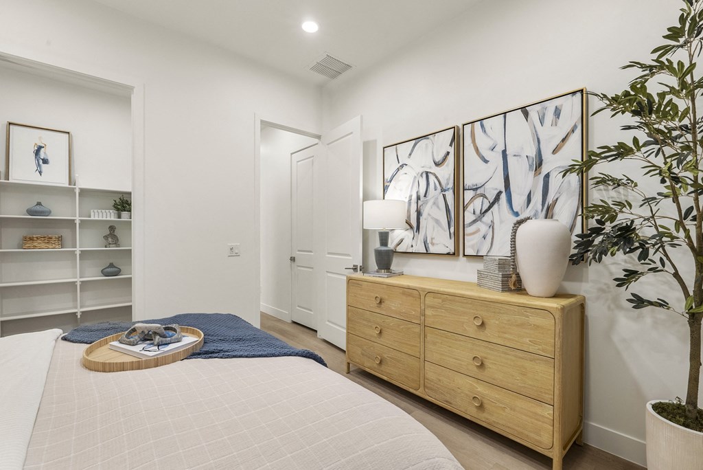 A bedroom with a bed, dresser, and a painting on the wall.