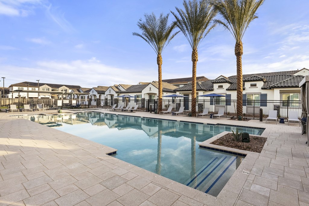 A swimming pool surrounded by palm trees and a residential area.