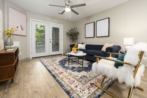 A living room with a black couch and a rug.