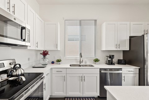 a kitchen with white cabinets and black appliances and a window