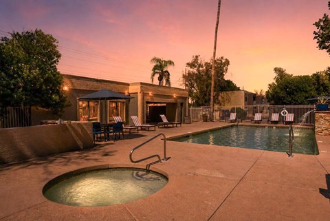 A pool with a hot tub and a building in the background.