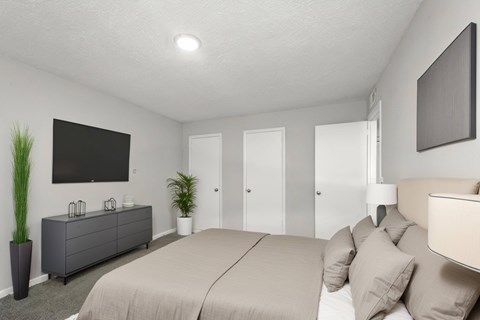 A bedroom with a large bed and a flat screen TV mounted on the wall.