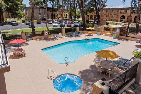 A large swimming pool with a hot tub in the middle of a patio area.