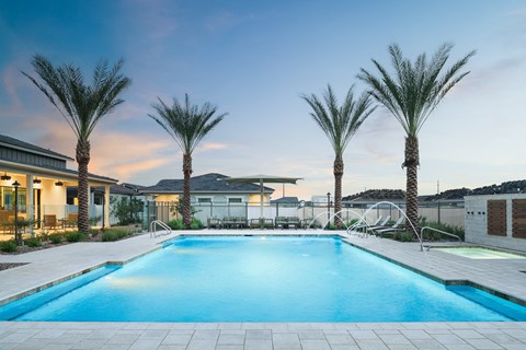 A swimming pool surrounded by palm trees and a building in the background.