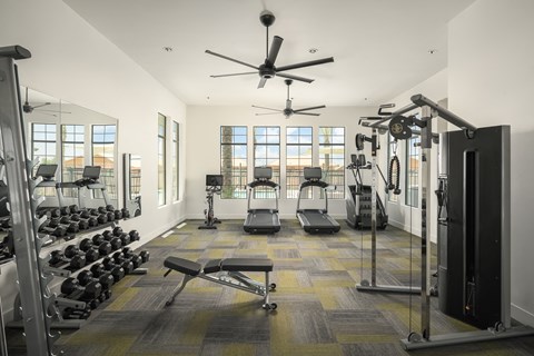 A spacious gym with a variety of equipment and a ceiling fan.