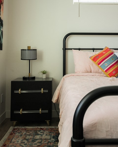 A bedroom with a bed, a nightstand with a lamp, and a rug.
