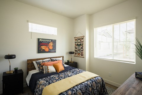 A bedroom with a bed, a lamp, a wall hanging and a window.