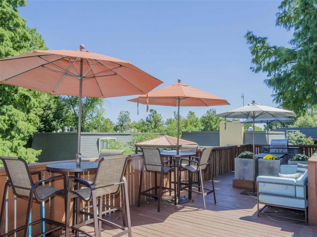 A patio with a table and chairs under umbrellas.