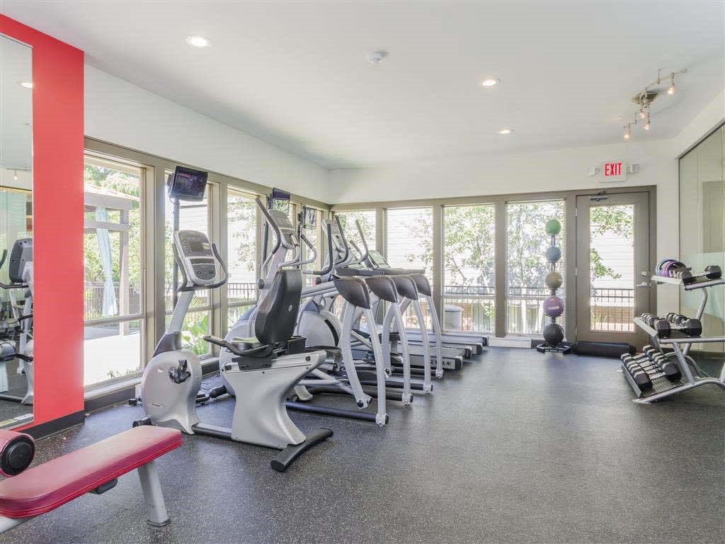 A gym with a variety of equipment including treadmills, weights, and exercise machines.