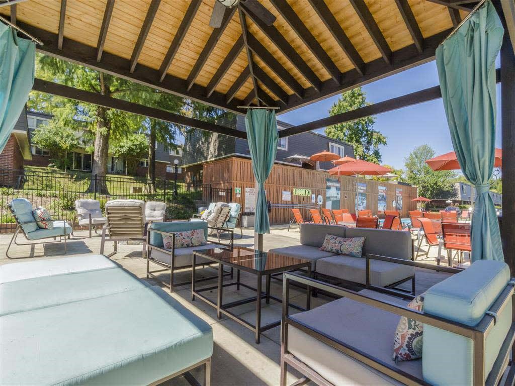 A patio with a table and chairs under a wooden roof.