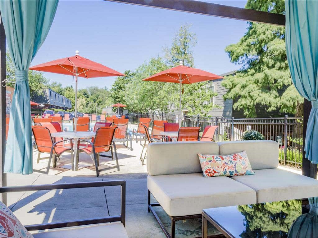 A patio with red umbrellas and chairs.