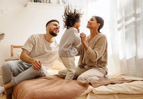 a man and woman sitting on a bed with a child