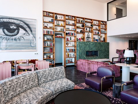 A living room with a large eye painting on the wall and a bookshelf filled with books.