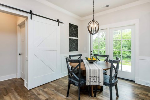 A dining room with a white door and a table with chairs.