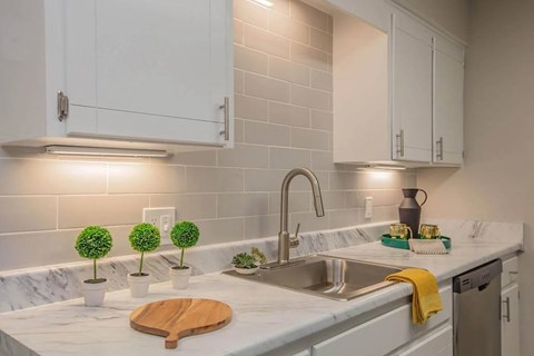 A kitchen with white cabinets and a marble countertop.