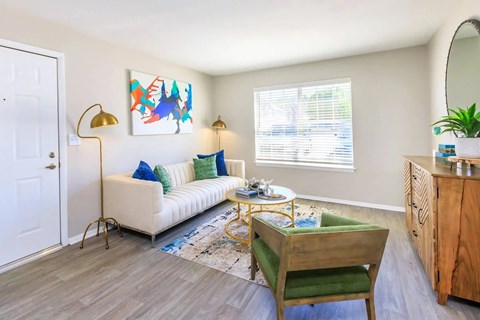 A living room with a white couch, a yellow chair, and a painting on the wall.