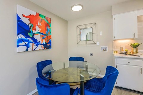 A dining room with a glass table and blue chairs.