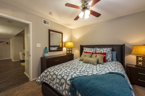 A bedroom with a bed, nightstands, and a ceiling fan.