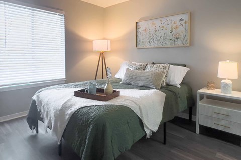 A bedroom with a bed, nightstand, and a painting on the wall.